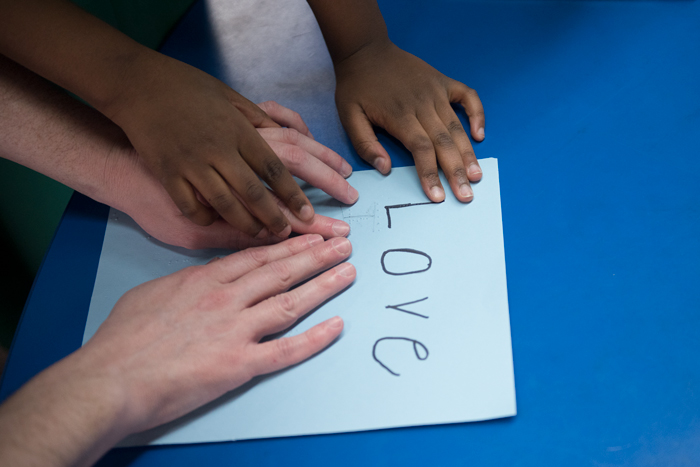 Hands reading the word "love" in braille