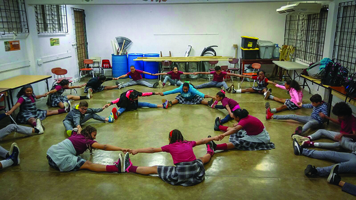 Students lined up in circles, stretching and holding each others' hands.