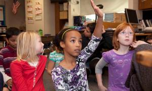 girl raising hand with peers in class