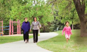 Photo of two adults holding hands while a happy child run at the park