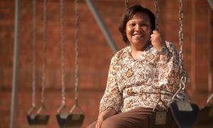 A woman sits on a swingset