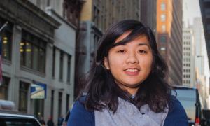 A student stands in front of a cityscape.