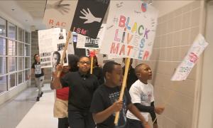 Kids marching in the school hallway with BLM signs