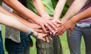 Young people put their hands together in solidarity.