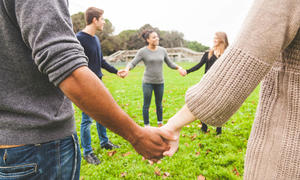 Young people stand in a circle holding hands