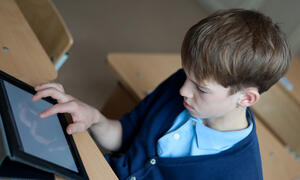 boy in school uniform looking at ipad