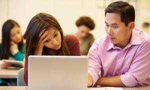 teacher helping stressed student with computer work