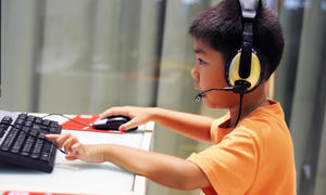 Boy uses computer with headphones on