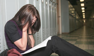 girl reading with face in hands sitting on hallway floor