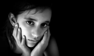 girl with face in hands looking sad in black and white