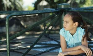 pensive determined youth of color leaning on playground