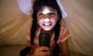 girl holding flashlight to her face