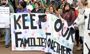 Immigrant families and allies gather behind a sign that reads, "Keep our families together."