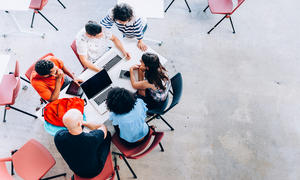 Group of students and teacher sitting around table having a discussion