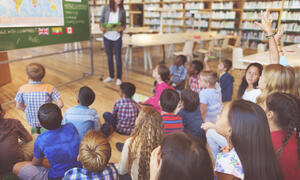 Young student raising hand to ask question during class lecture