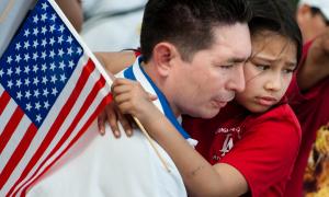 Young child holding American flag being held by adult.