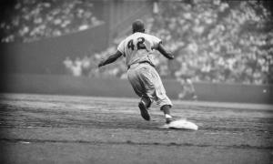 Jackie Robinson rounding first base at baseball game.