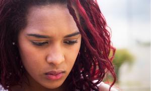 High school-aged student with red-colored hair looking downcast and pensive.