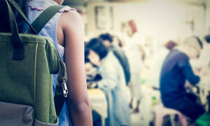 Young student with back to the viewer wearing a backpack. 