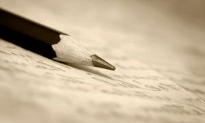 A pencil sitting on top of a sheet of paper with writing on it.