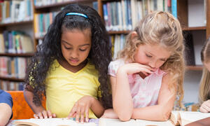 Two young students reading separate books.