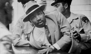 Dr. Martin Luther King, Jr. being detained and arrested by uniformed police officers.