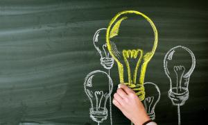 Lightbulbs drawn in yellow and white chalk on a chalkboard.