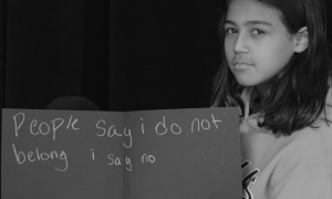 Young student holding sign that says "People say I do not belong I say no."