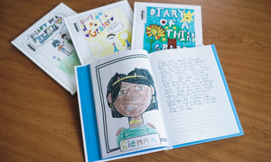 Several student-created books on a table, with the top one opened to a page featuring a drawing of a person of color named Sienna.