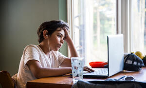 Young person sitting in front of a laptop computer.