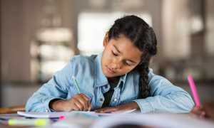 Young child writing in notebook.