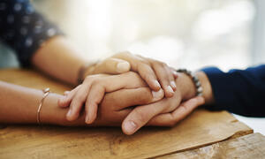 Two people hold hands in support of each other. 