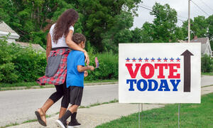 Going to Vote - a Black adult and child walking with "Vote Today" sign on sidewalk.
