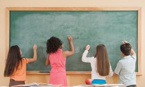 Kids writing on a chalk board.