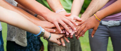 Young people put their hands together in solidarity.