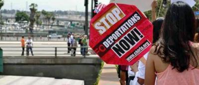 AFT link photo of protestor holding sign that says "Stop deportations now!"