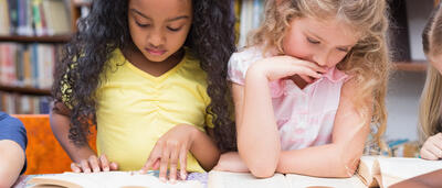 Two young students reading separate books.