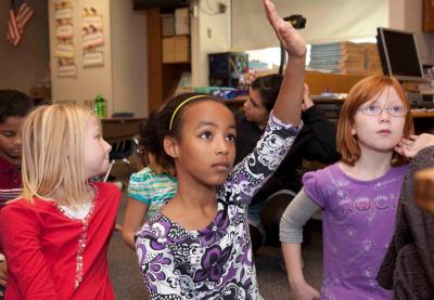girl raising hand with peers in class