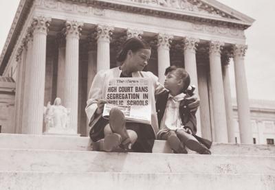 Mother and daughter hold Newspaper with headline "High Court Bans Segregation In Public Schools"