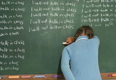 Child writing on the chalkboard "I will not talk in class"