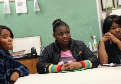 Three black students listen at a table