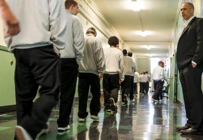 A teacher watches his students pass him in the hallways of a youth correctional facility