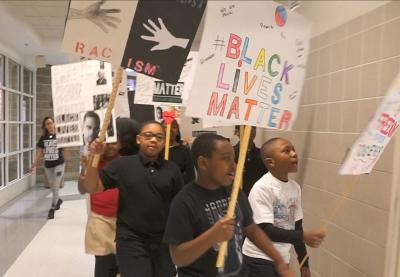 Kids marching in the school hallway with BLM signs