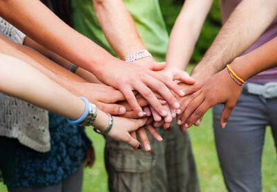 Young people put their hands together in solidarity.