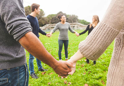 Young people stand in a circle holding hands