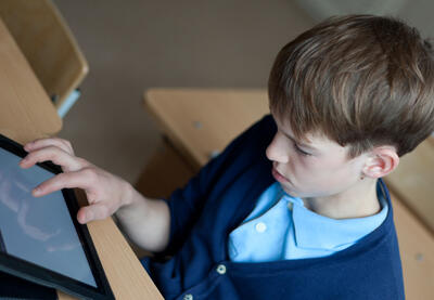 boy in school uniform looking at ipad