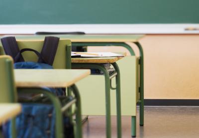 desk with backpack in empty classroom