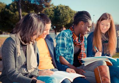 students looking over homework sitting on bench outside