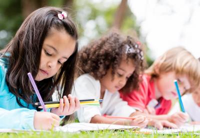 young students coloring lying on grass