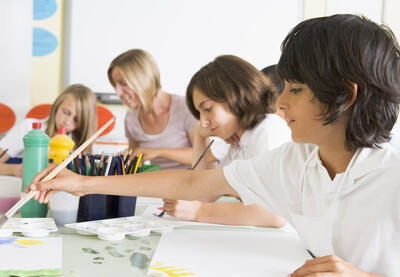 boy painting with classmates